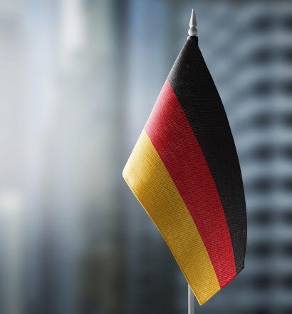 A small flag of Germany on the background of an urban abstract blurred background.